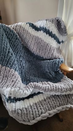 Blue, grey, and white striped chunky knit blanket on a wooden chair